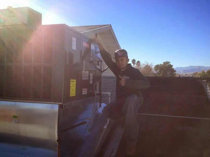 HVAC technician performing AC Tune-Up on a rooftop unit in Wrentham